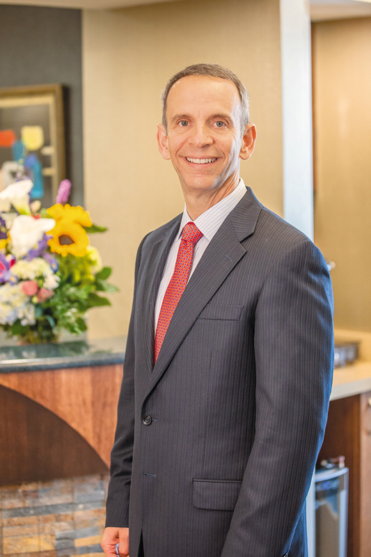 Dr. David R. Scharf standing side profile in a suite in his clinic.