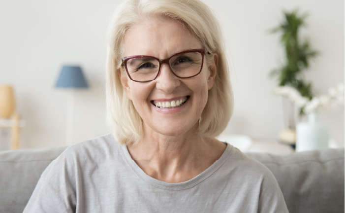 female with glasses at home smiling toward camera