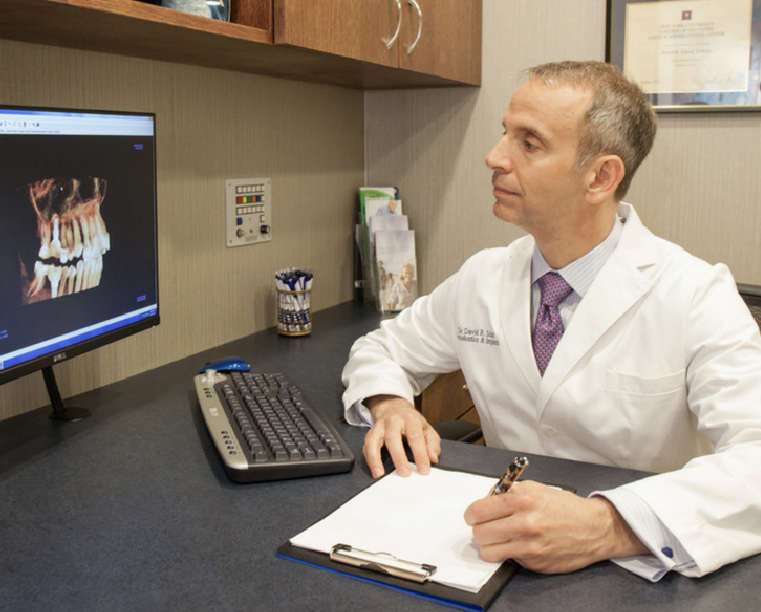 Dr. Scharf at his office desk look at a dental scan