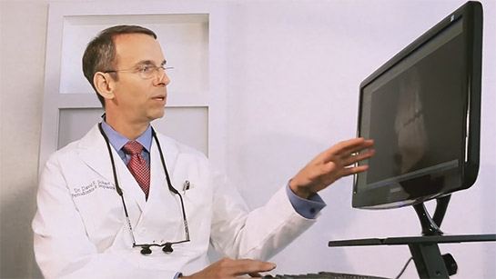 Dr. Scharf pointing at a computer monitor showing X-ray