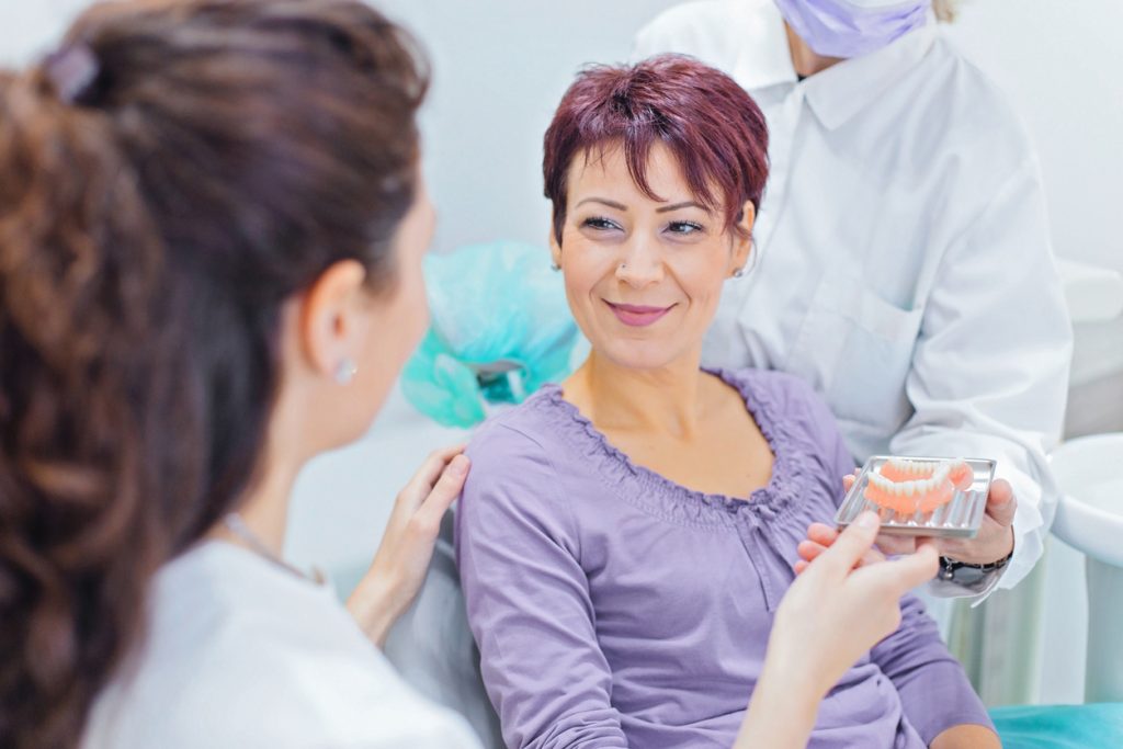 Dentist showing teeth dentures to a patient