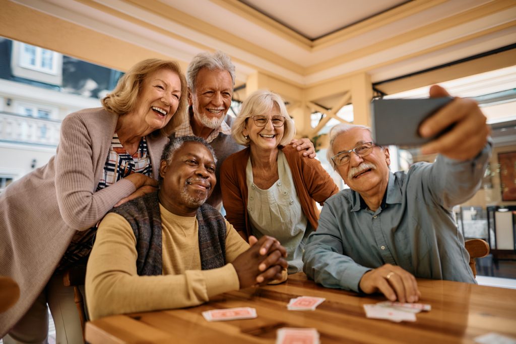 Multiracial group of happy senior people taking selfie with cell phone