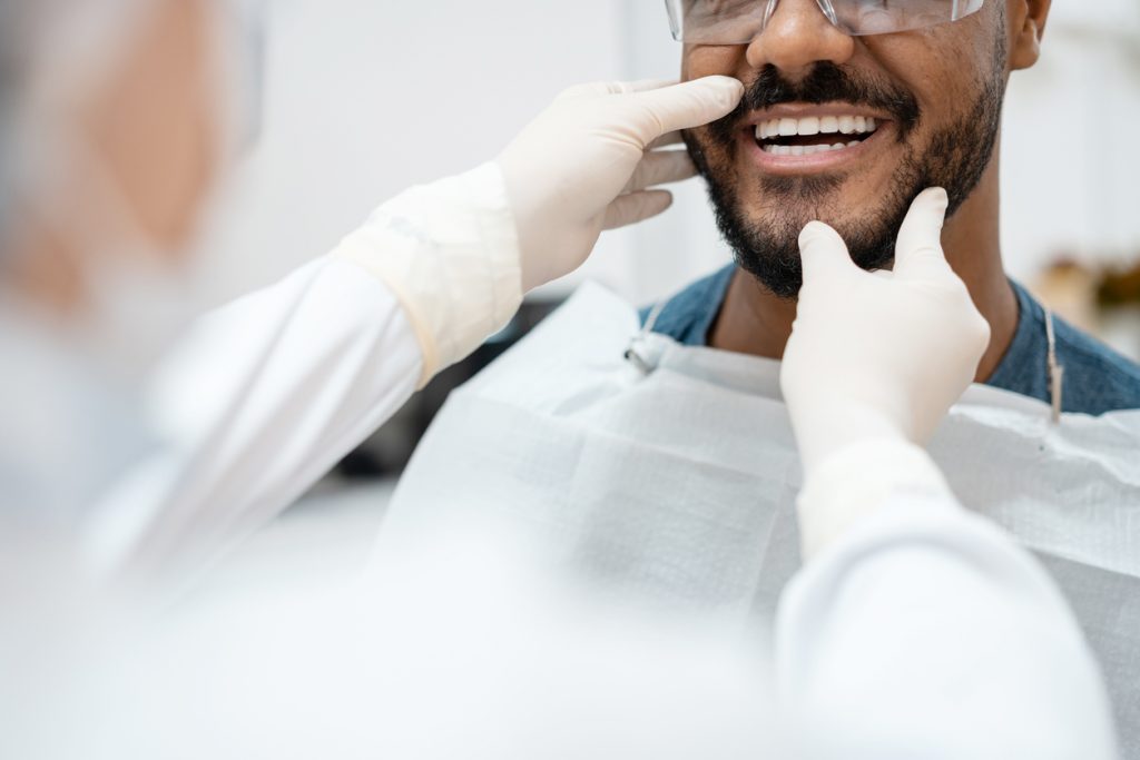 Periodontist examining a male patient's teeth and bite