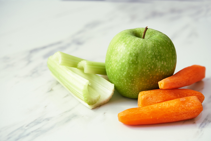 Green apple, carrots, and celery on a marble counter