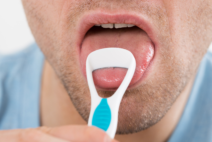 Man using a tongue scraper