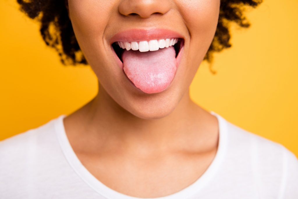 Woman sticking out her tongue over a yellow backdrop