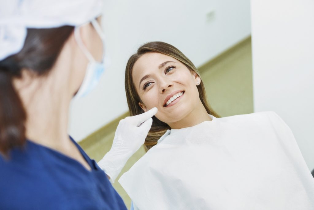 A woman in a dental chair the dental assistant pointing at her gums