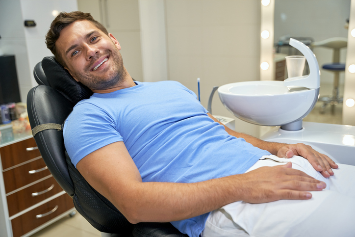 male dental patient in dental chair smiling.