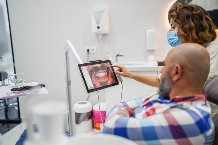 Dental implant patient with a dental assistant looking at a digital scan.