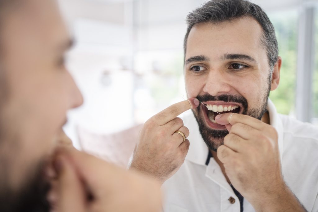 Man flossing his teeth to keep healthy gums