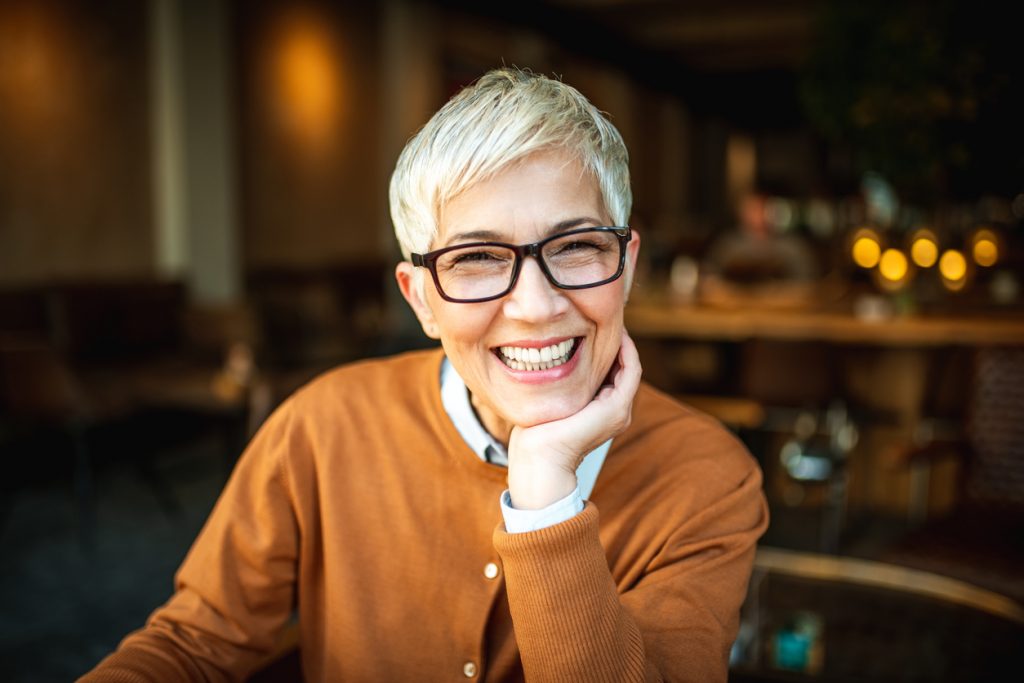 Woman smiling with either dentures of dental implants
